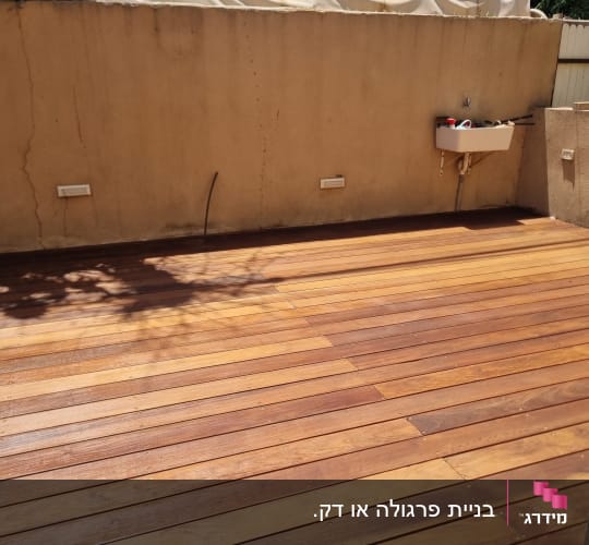 דק עץ חום בחצר עם קיר ומזגן